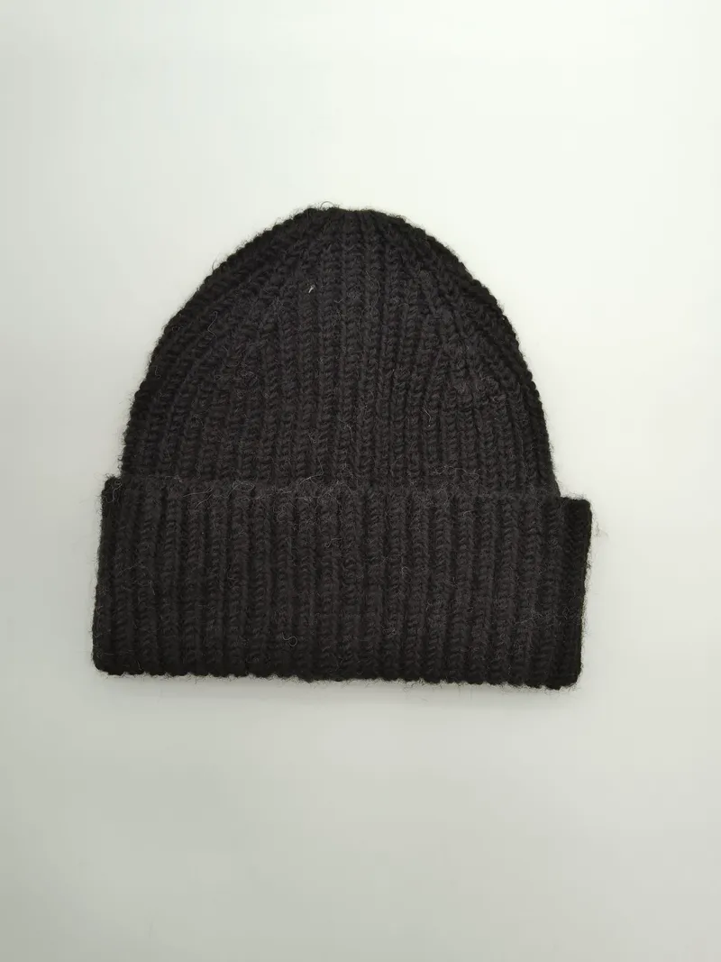 Schwarze Strickmütze mit grobem Rippenmuster und breitem Krempenumschlag, Draufsicht auf weißem Untergrund, warme Wintermütze