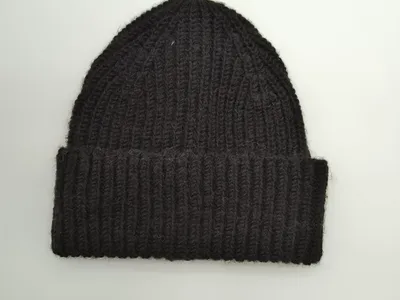 Schwarze Strickmütze mit grobem Rippenmuster und breitem Krempenumschlag, Draufsicht auf weißem Untergrund, warme Wintermütze