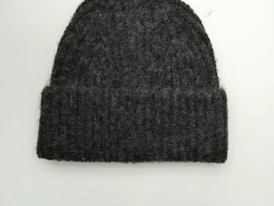 Dunkel anthrazitgraue Strickmütze mit flauschiger Wollstruktur und gefaltetem Krempenumschlag, Flachbild auf weißem Hintergrund