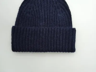Marineblaue Strickmütze mit breitem Krempenumschlag aus grobem Rippenstrick, Draufsicht auf weißem Hintergrund