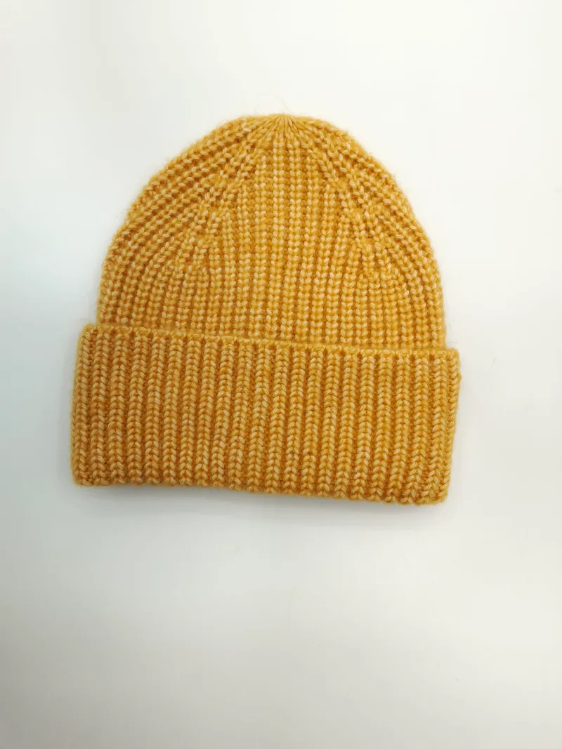 Senfgelbe Strickmütze mit breitem gefalteten Bund aus Rippenstrick, flach auf weißem Untergrund fotografiert