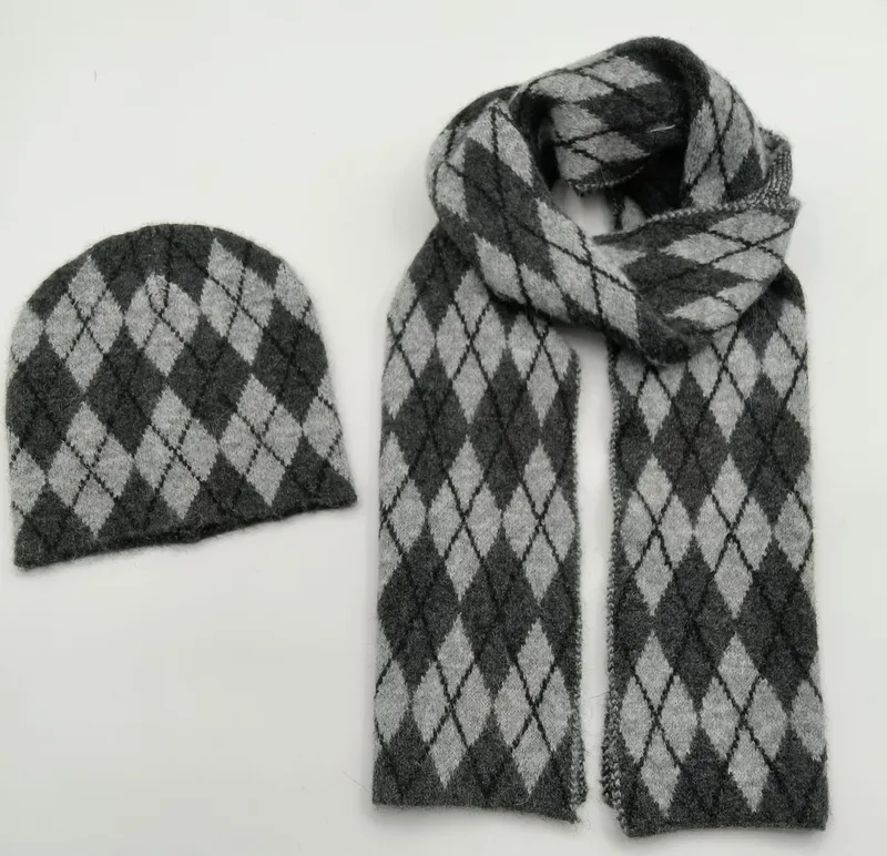 Aufeinander abgestimmtes Strickset aus Mütze und Schal mit Argyle-Rautenmuster in Anthrazit und Hellgrau, Draufsicht auf weißem Hintergrund