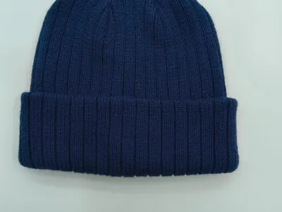 Marineblaue Wintermütze mit Rippenmuster und umgeschlagenem Rand, weicher Strickstoff, Draufsicht auf weißem Hintergrund