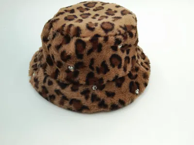 Flauschiger Bucket Hat im Leo-Print aus Kunstfell in Beige-Braun-Tönen mit funkelnden Kristallsteinchen als Dekoration, Produktfoto auf weißem Untergrund