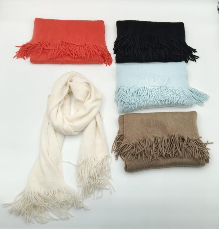 Fünf weiche Fransenschals in Creme, Schwarz, Rot, Hellblau und Beige auf weißem Hintergrund, einer offen drapiert