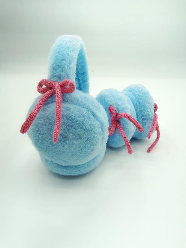 Weiche Ohrenschützer in Babyblau aus Kunstfell mit gestrickter rosa Schleifendekoration – Detailaufnahme auf hellem Untergrund