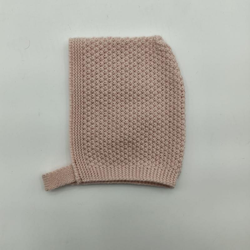 Flach gelegte, zartrosa Babymütze in Perlstricktextur mit geripptem Kinnband auf weißem Hintergrund