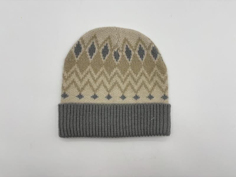 Beigefarbene Strickmütze mit grauem Fair-Isle-Rauten- und Zickzackmuster sowie grauem Rippenbündchen, Flachlage auf weißem Hintergrund