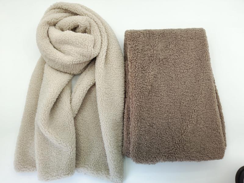 Zwei Sherpa-Fleece-Schals in Beige und Taupe, einer drapiert und einer flach gefaltet, mit sichtbarer Teddybär-Plüschstruktur