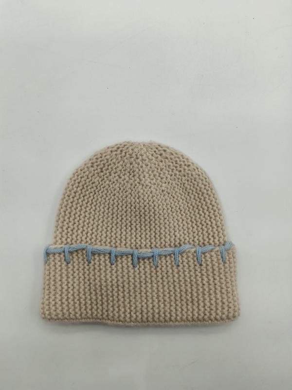 Cremefarbene Wintermütze aus dickem Garn mit auffälliger blauer Kontrastnaht entlang des gefalteten Randes, Studioaufnahme