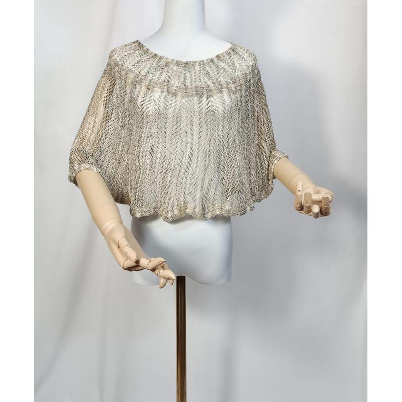 Kurzer Häkelponcho in Beige und Gold auf Schneiderpuppe, Diamant-Mesh-Muster, weite Fledermausärmel, Holzhände sichtbar