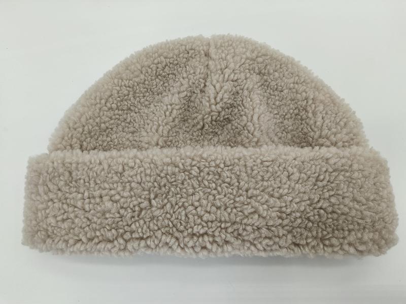 Beigefarbene Sherpa-Fleece-Mütze mit lockig-strukturiertem Stoff und umgeschlagenem Rand, Flachaufnahme auf weißem Hintergrund