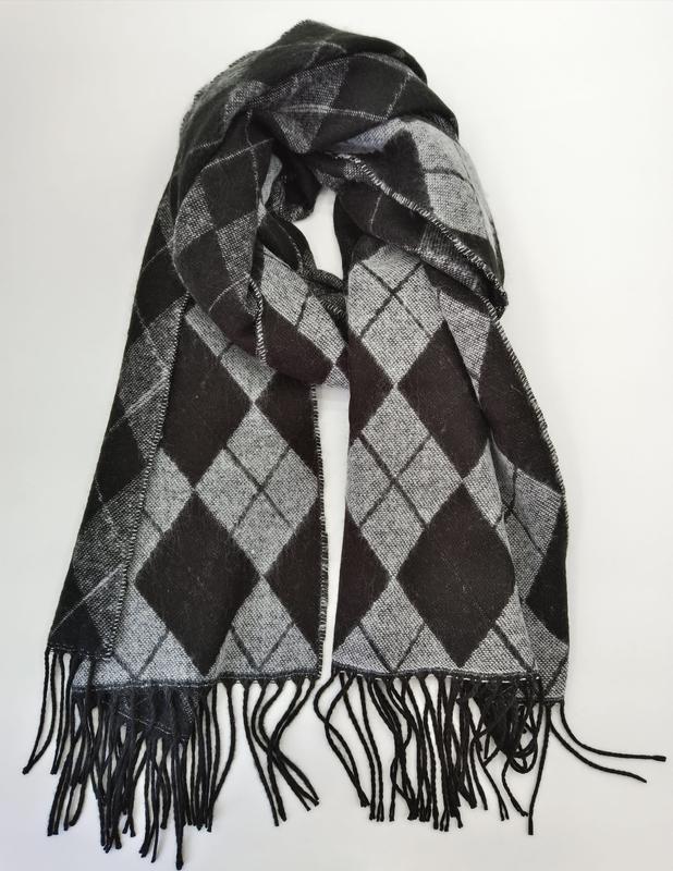 Gestrickter Winterschal in Schwarz und Grau mit klassischem Rautenmuster und langen schwarzen Fransen, flach auf weißem Untergrund