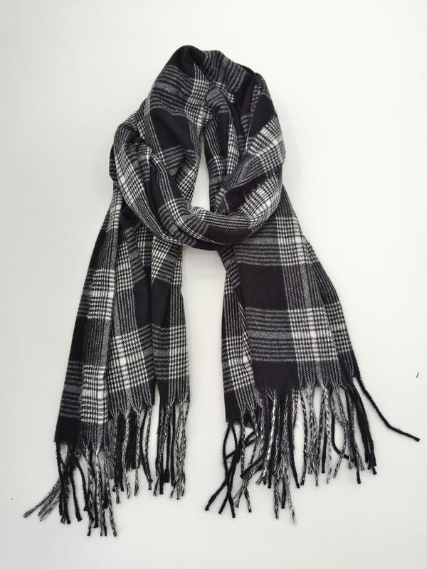 Klassischer Tartan-Schal in Schwarz-Weiß mit geometrischem Karomuster und geknoteten Fransenenden, locker gefaltet auf weißem Untergrund