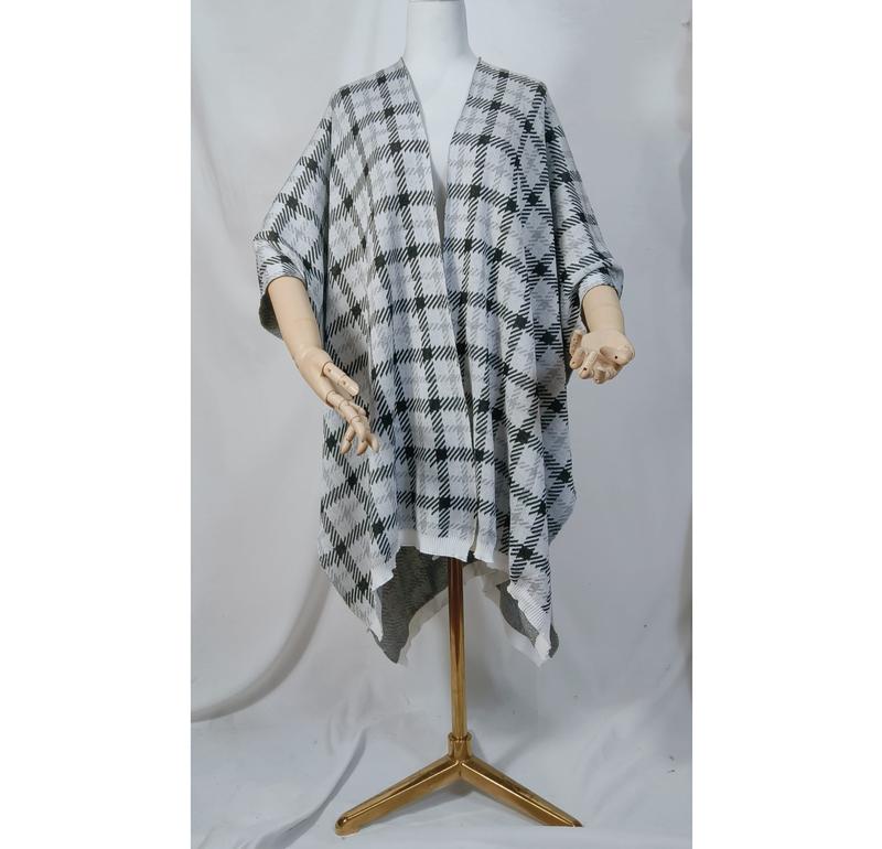 Schneiderpuppe mit schwarzem und weißem Karomuster-Strickponcho, offenem Vorderteil und asymmetrischem Saum auf goldenem Ständer
