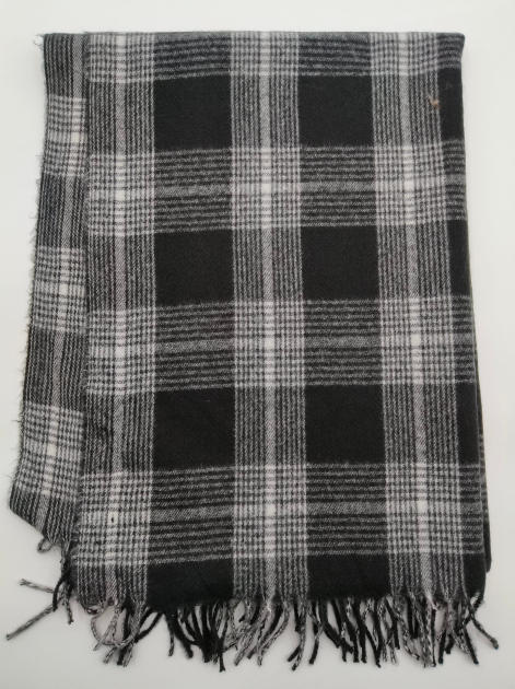Zusammengelegte schwarz-weiße Tartan-Karierwolldecke aus gewebtem Stoff mit geknoteten Fransenenden auf weißem Hintergrund