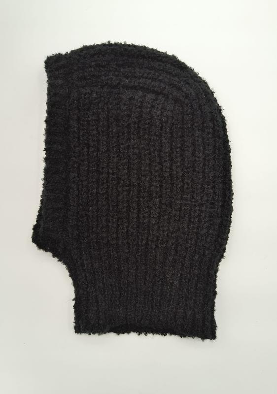 Schwarze Vollsturmhaube aus bouclétexturiertem Grobstrick, flach auf weißem Hintergrund mit fransigen Garnenden und ausgeprägter Wollstruktur