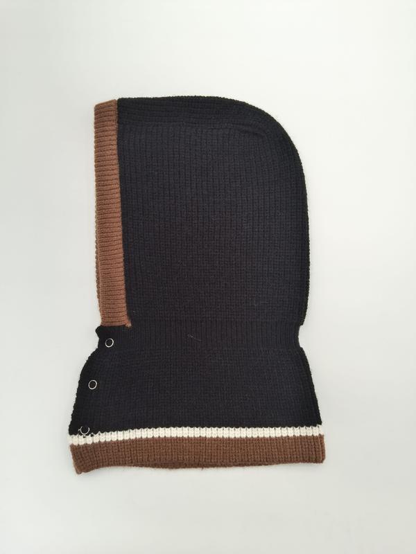 Schwarze Rippenstrick-Balaclava mit braunem Rand, cremefarbenem Streifenakzent und silbernen Druckknöpfen, freigestellt auf weißem Hintergrund