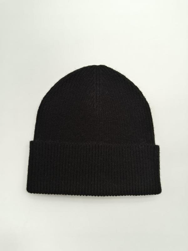 Schwarze Rippstrickmütze mit breitem umgeschlagenem Rand flach auf weißem Untergrund, weiche Wintermütze