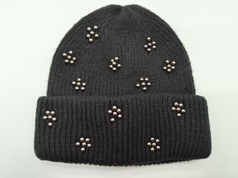 Schwarze Umschlag-Beanie aus Rippenstrick mit dekorativen silbernen Metallperlen in Blütenform auf der Krempe