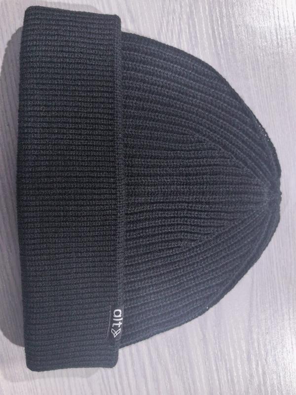 Schwarze Rippstrickmütze mit gefaltetem Bündchen auf hellem Untergrund – gleichmäßige Stricktextur und klar definierter Krempenfalz sichtbar