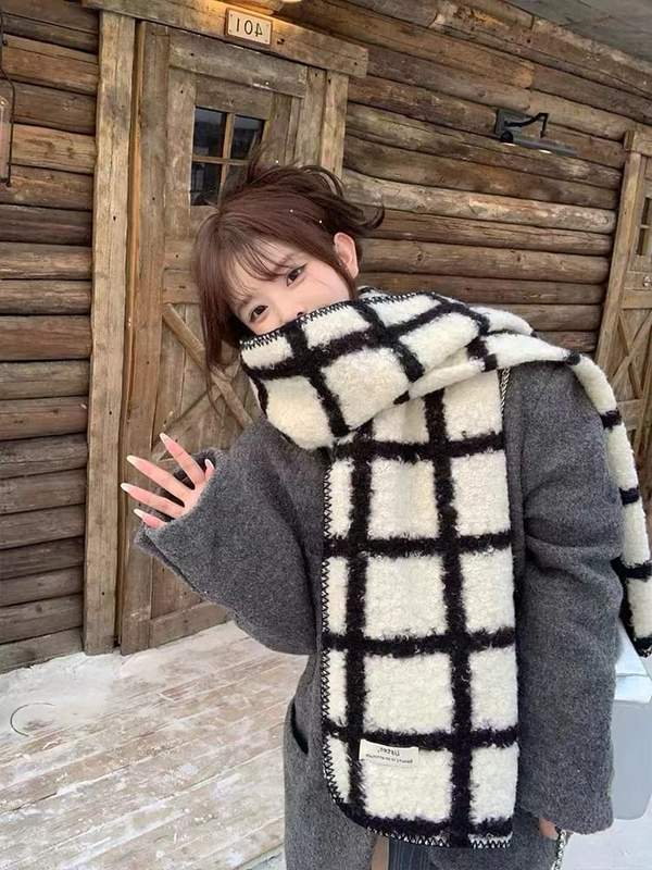 Großer Sherpa-Wollschal in kontrastreichem Schwarz-Weiß-Karo, leger über einem grauen Mantel getragen, winterliche Naturkulisse