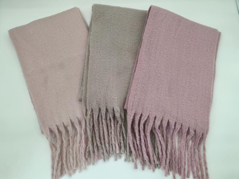 Drei gefaltete Bouclé-Schals mit Fransen in den Farben Altrosa, Taupe und Mauve auf weißer Unterlage