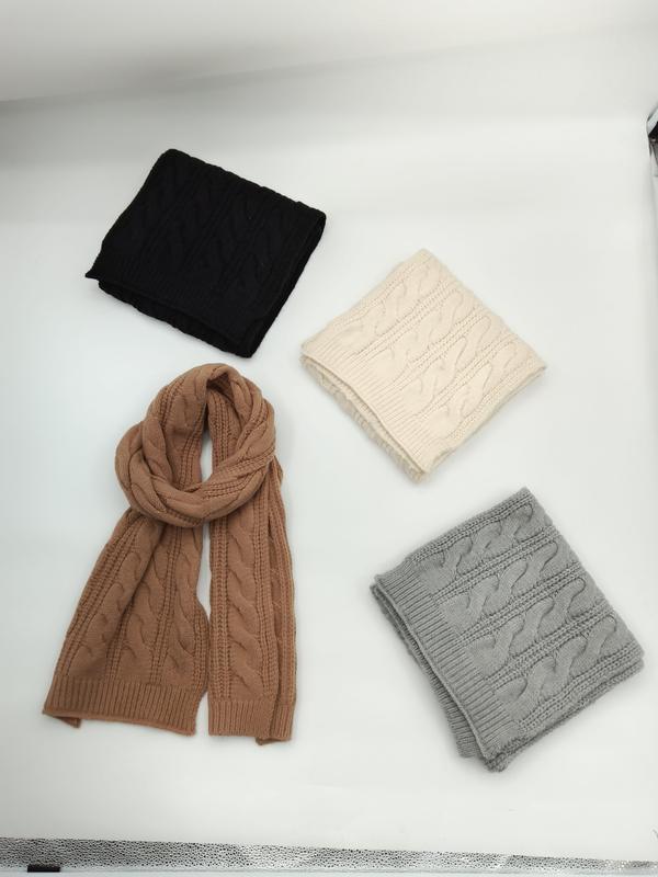 Vier gefaltete Strickschals mit Zopfmuster in den Farben Anthrazit, Elfenbein, Kamelbraun und Hellgrau auf hellem Untergrund, einer ausgebreitet in voller Länge