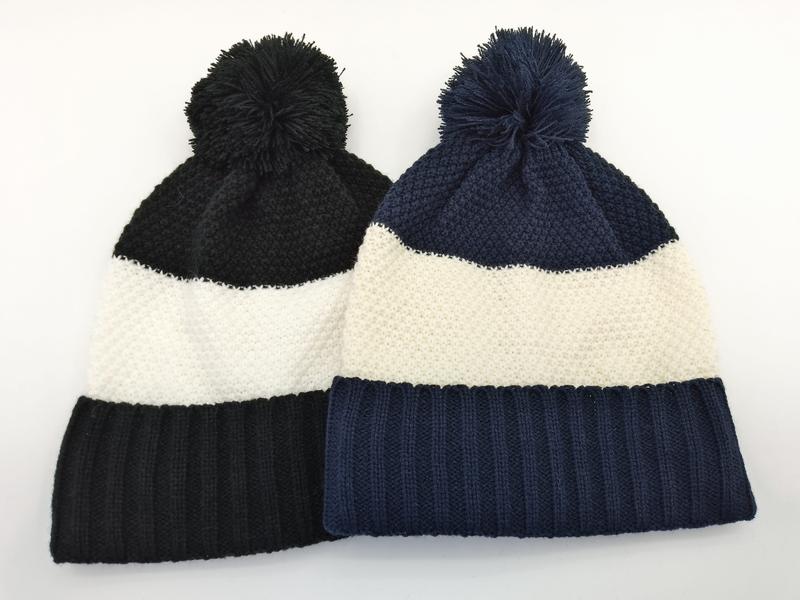 Zwei Strick-Bommel-Beanies in Schwarz-Weiß und Marine-Weiß Streifenmuster nebeneinander auf weißem Hintergrund