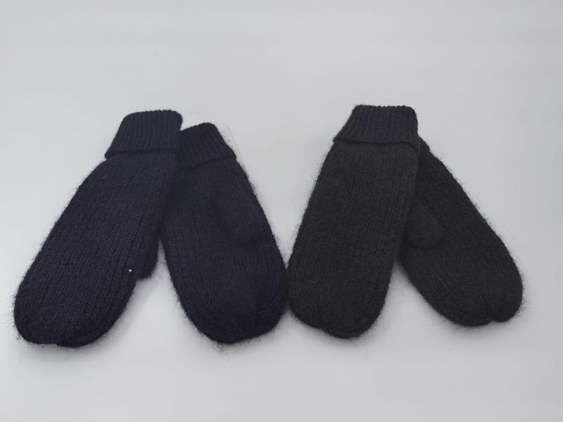 Zwei Paar klobige Strickfäustlinge in Schwarz und tiefem Dunkelbraun nebeneinander auf weißem Untergrund mit sichtbaren Rippbündchen und flauschiger Oberfläche