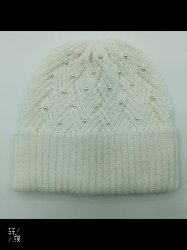 Weiche Wintermütze in Weißcreme mit Flechtmuster und aufgenähten Perlen als modisches Accessoire auf hellem Untergrund