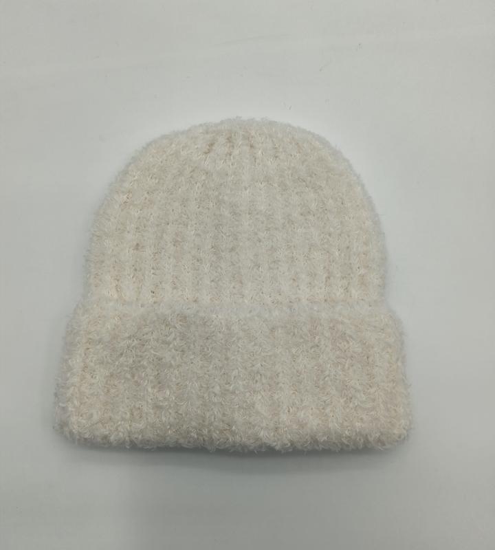 Weiche cremeweiße Wintermütze mit fluffiger Strickstruktur und lockerem Sitz, von oben fotografiert auf hellem Untergrund