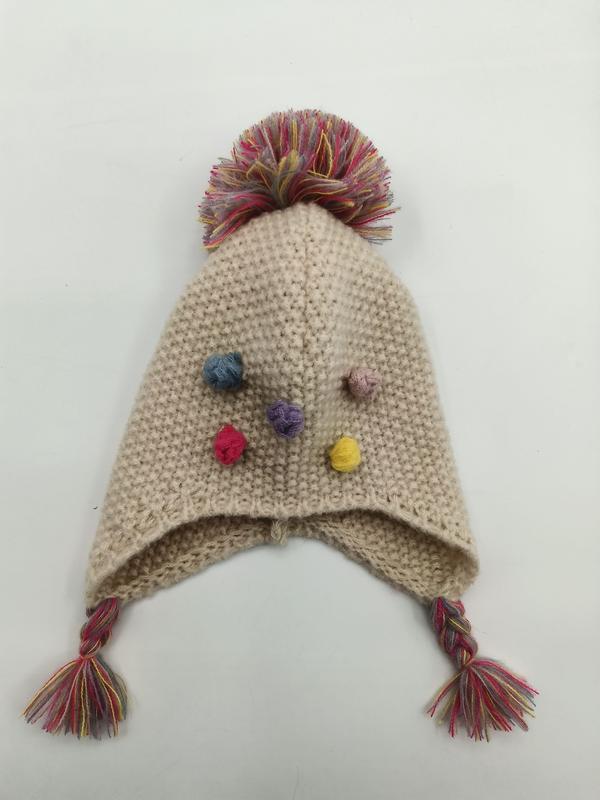 Handgestrickte Creme-Baby-Ohrenklappenmütze mit großem mehrfarbigem Pompon, kleinen bunten Mini-Pompons und geflochtenen Quastenbändern