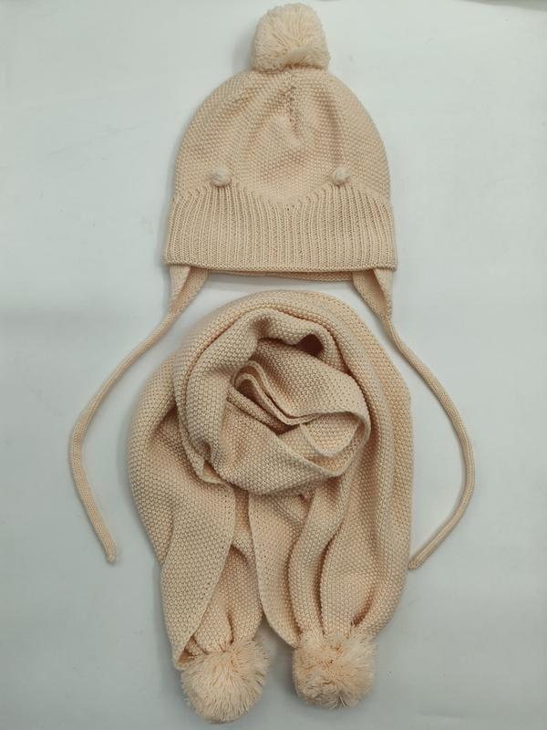Cremefarbenes Kinderstrick-Set: Beanie mit Pompon und Ohrenschutz sowie zugehöriger Strickschal mit Pomponenden