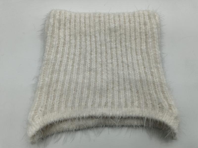 Nahaufnahme eines cremebeigefarbenen Rippenstrick-Stoffmusters mit weichem Mohair-Heiligenschein-Effekt, flach gefaltet auf weißem Hintergrund