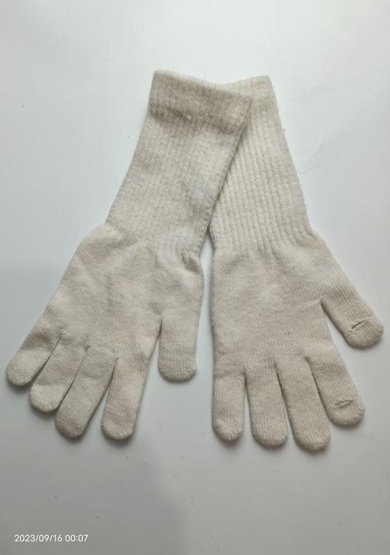 Paar cremefarbene Strick-Handschuhe mit langen Strickbündchen flach auf weißem Untergrund liegend, Handflächen sichtbar