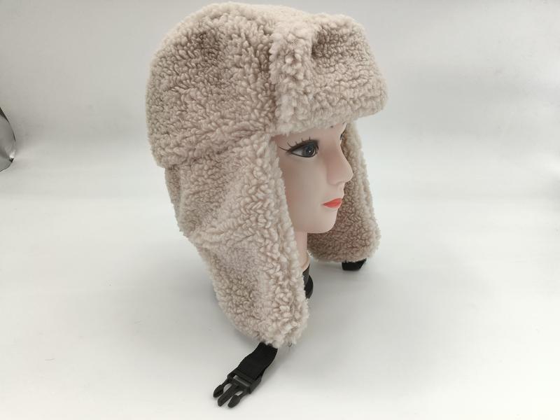 Cremefarbener Sherpa-Ushanka-Trapperhut mit Ohrenschutzklappen und schwarzem Kunststoffschnallen-Kinnriemen auf Hutständer
