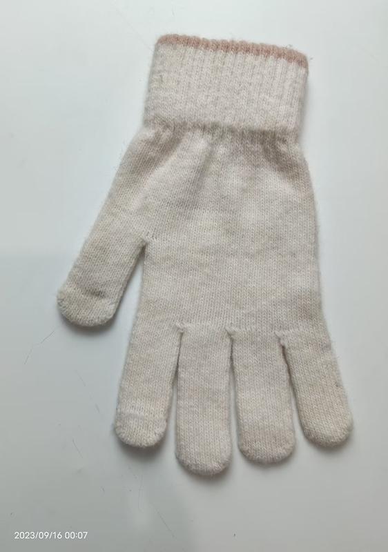 Ein einzelner cremefarbener Winterhandschuh mit geripptem Abschluss und zartem rosa Streifen-Detail, Draufsicht auf weißem Untergrund
