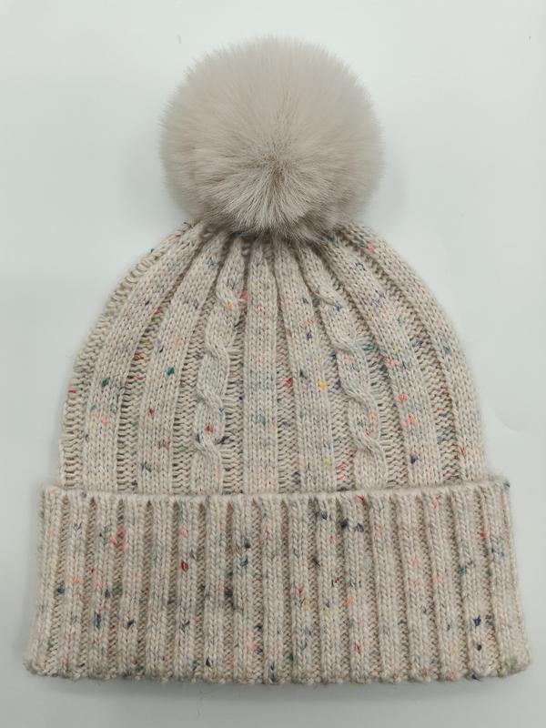 Cremefarbene Zopfstrickmütze mit bunten Farbsprenkeln und großem flauschigem Kunstfell-Bommel auf der Spitze
