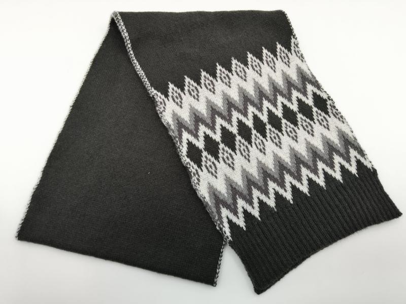 Gefalteter Anthrazit-Strickschal mit weiß-grauem Fair-Isle-Zickzack-Muster und gerippten Abschlussenden, Draufsicht