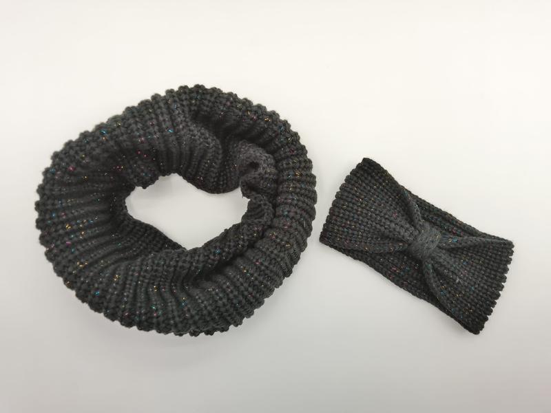 Dunkelgrauer Infinity-Schal aus Grobstrick neben passendem Schleifenhaarband mit farbigen Metallic-Lurexfäden auf weißem Hintergrund