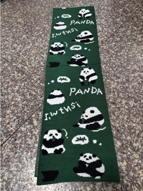 Dunkelgrüner Wollschal mit gestrickten Panda-Illustrationen und PANDA-Schriftzug, flach auf Fliesenboden liegend