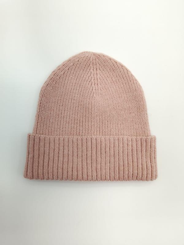 Strickmütze in gedämpftem Rosaton mit breitem gefaltetem Bündchen auf weißem Hintergrund, flach fotografiert