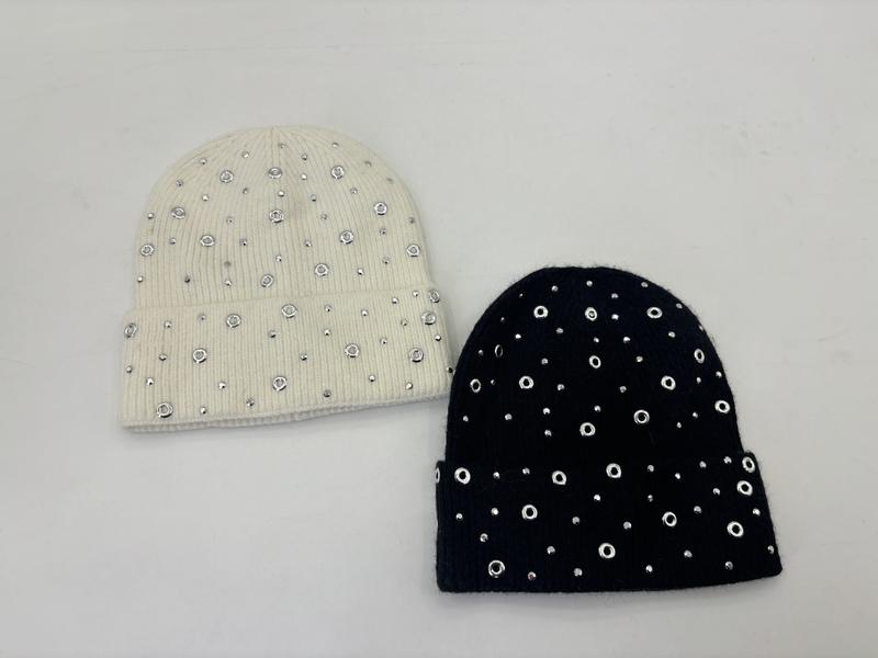 Zwei Rippstrickmützen in Creme und Schwarz mit silbernen Ösenringen und Strasssteinen dekoriert, auf weißem Hintergrund