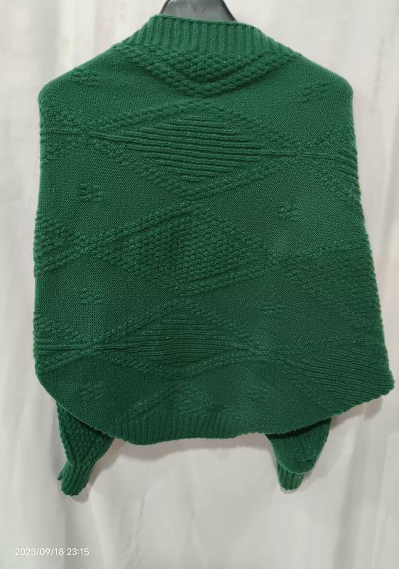 Rückansicht eines smaragdgrünen Strick-Ponchos mit erhabenem Rautenmuster auf einem Kleiderbügel