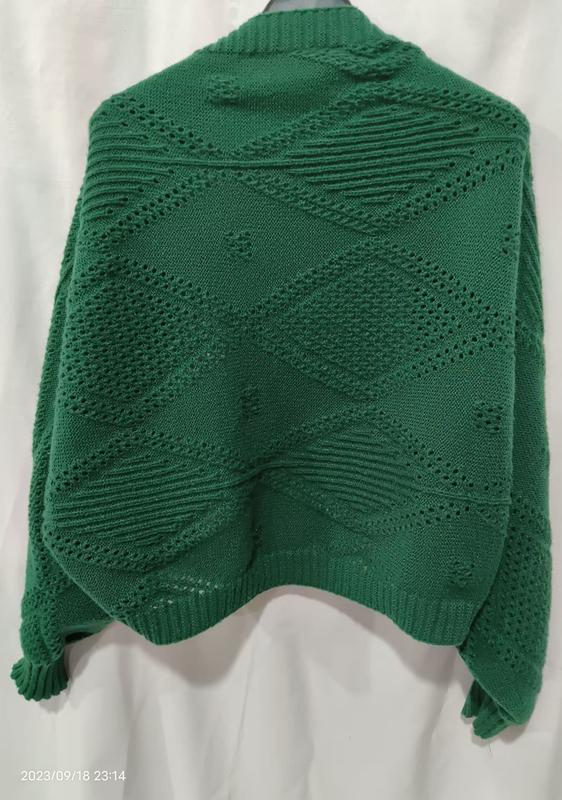 Rückenansicht eines smaragdgrünen Oversize-Strickpullovers mit Rautenmuster-Lochdurchbrüchen und Rippenbund auf Schneiderpuppe