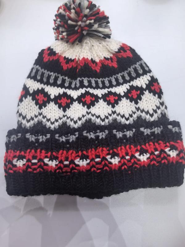 Handgestrickte Fair-Isle-Wintermütze in Schwarz, Rot, Weiß und Grau mit buntem Wollbommel auf der Spitze