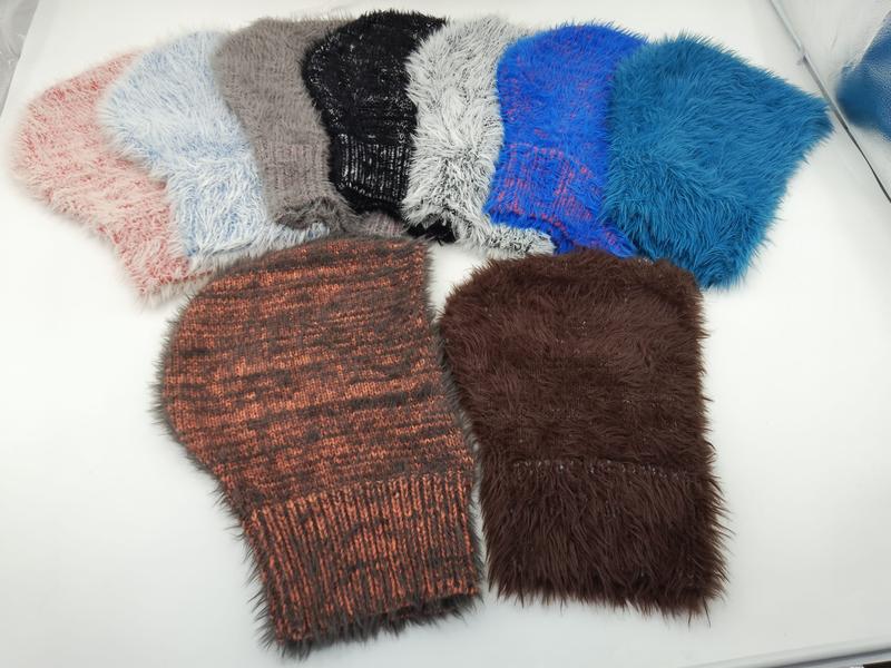 Sieben flauschige Wintermützen aus Kunstfell und Grobstrick in Pink, Grau, Schwarz, Weiß, Blau, Rostrot und Braun auf hellem Untergrund