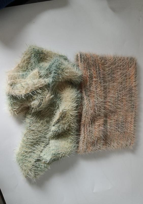 Zwei Eyelash-Garn-Strickproben in Salbeigrün und Altrosa auf weißem Untergrund