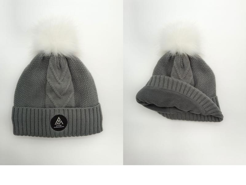 Warme Wintermütze in Grau mit grobem Zopfstrickmuster, flauschigem Fellbommel und sichtbarem Fleece-Innenfutter
